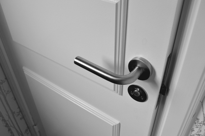 A technician installs silver accessibility hardware on a commercial door.